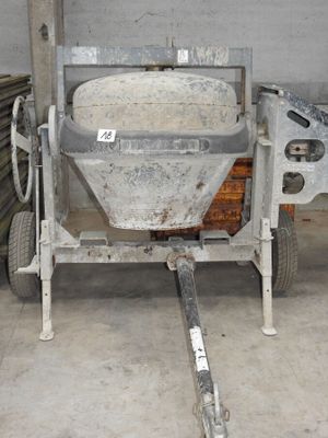 une bétonnière dans un garage, avec une brouette en arrière-plan