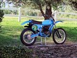 a blue dirt bike parked in front of a white fence