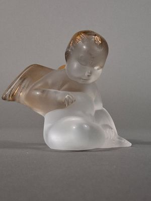 une figurine en verre représentant un bébé assis sur un nuage