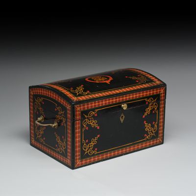 une petite boîte noire et rouge ornée de motifs dorés