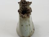 a small vase with a flower in it on a white surface