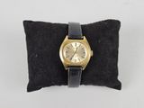 an image of a gold wrist watch on a black pillow