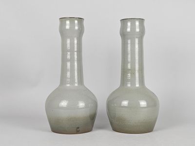 two gray vases sitting next to each other on a white surface