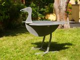 a metal duck that is standing in the grass