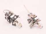 pair of earrings with leaves and pearls on them on a white surface