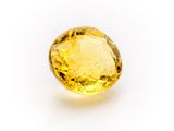 a close up of a yellow sapphire stone on a white surface