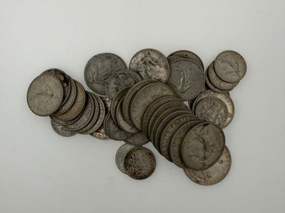a pile of old silver coins on a white surface