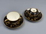 deux tasses et soucoupes ornées de motifs noirs et dorés