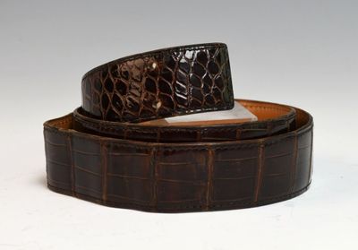brown alligator skin belt with a silver buckle on a white background