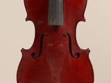 an old red violin sitting on top of a white surface