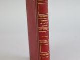 an old red book sitting on top of a table next to a white wall
