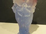 un vase bleu contenant une fleur rose, posé sur une table