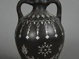 a black vase with white designs on it on a gray background