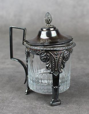 une théière en verre avec un couvercle en métal posée sur une table
