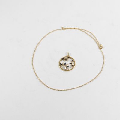 un collier composé d'une chaîne en or sur laquelle est fixée une fleur blanche