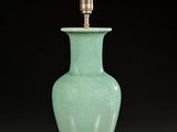 a green vase on a red table with a gold base