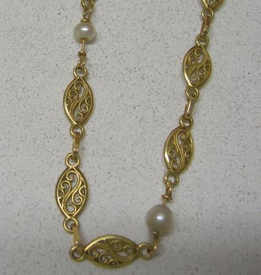 collier plaqué or orné de perles et de motifs en filigrane sur fond blanc