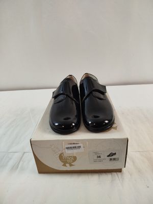 une paire de chaussures noires posée sur une boîte, elle-même posée sur une surface blanche
