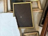 a pile of assorted framed and unframed items on a table