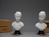 two white busts sitting next to each other in front of a box