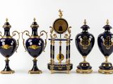 five vases and a clock on display in a row