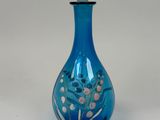 an image of a blue glass bottle with a flower design on it