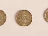 trois pièces d'or posées les unes à côté des autres sur une surface blanche