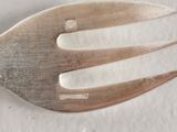 a silver fork with a silver handle on a white surface