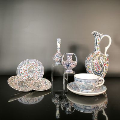 a glass table with a vase, plate, and cups on it