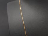 a gold chain necklace with a square pendant on a mannequin neck