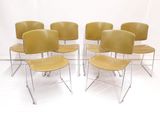 six chaises jaunes empilées les unes sur les autres dans une pièce blanche