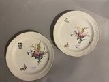 two plates with floral designs on them sitting on a table