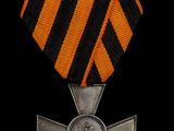 une médaille orange et noire ornée d'une croix argentée sur fond noir