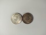two silver coins sitting next to each other on a white surface