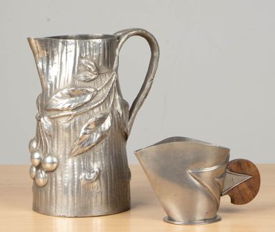 a silver pitcher sitting next to a teapot on a table