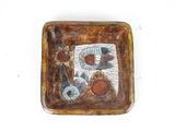 a brown plate with a picture on it on a white surface