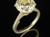 un gros plan d'une bague sertie d'un diamant jaune sur une surface noire