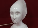 une tête de femme en céramique blanche dans laquelle est enfoncée une cuillère