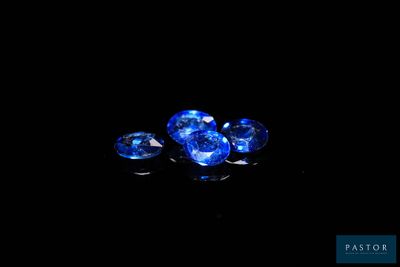 un gros plan sur trois saphirs bleus posés sur une surface noire