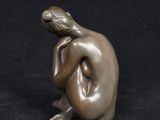 a bronze statue of a woman sitting on a black surface