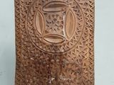 plaque en bois sculptée surmontée d'un vase, posée sur un fond blanc