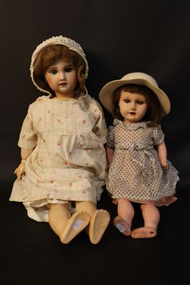 two dolls sitting next to each other on a black background