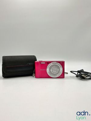 a pink camera and a black case on a white surface
