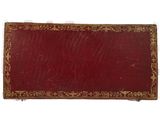 an old book with a red cover and gold trim