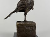 sculpture en bronze représentant un oiseau posé sur un rocher, sur fond blanc