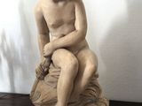 une petite statue représentant un garçon assis sur un rocher