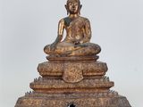 une statue antique de Bouddha en bronze, assise au sommet d'un tas de pierres