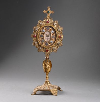 une horloge en or richement décorée, posée sur un socle surmonté d'une croix