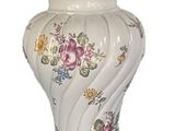 a white vase with flowers on it sitting on a table