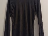 black long sleeved shirt hanging on a hanger against a white wall